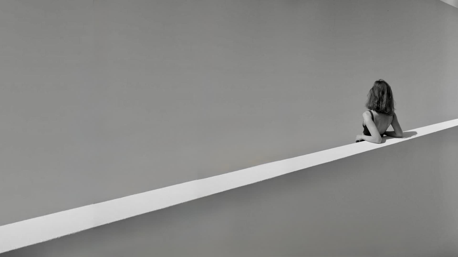 Woman sitting contemplatively on a minimalist ledge